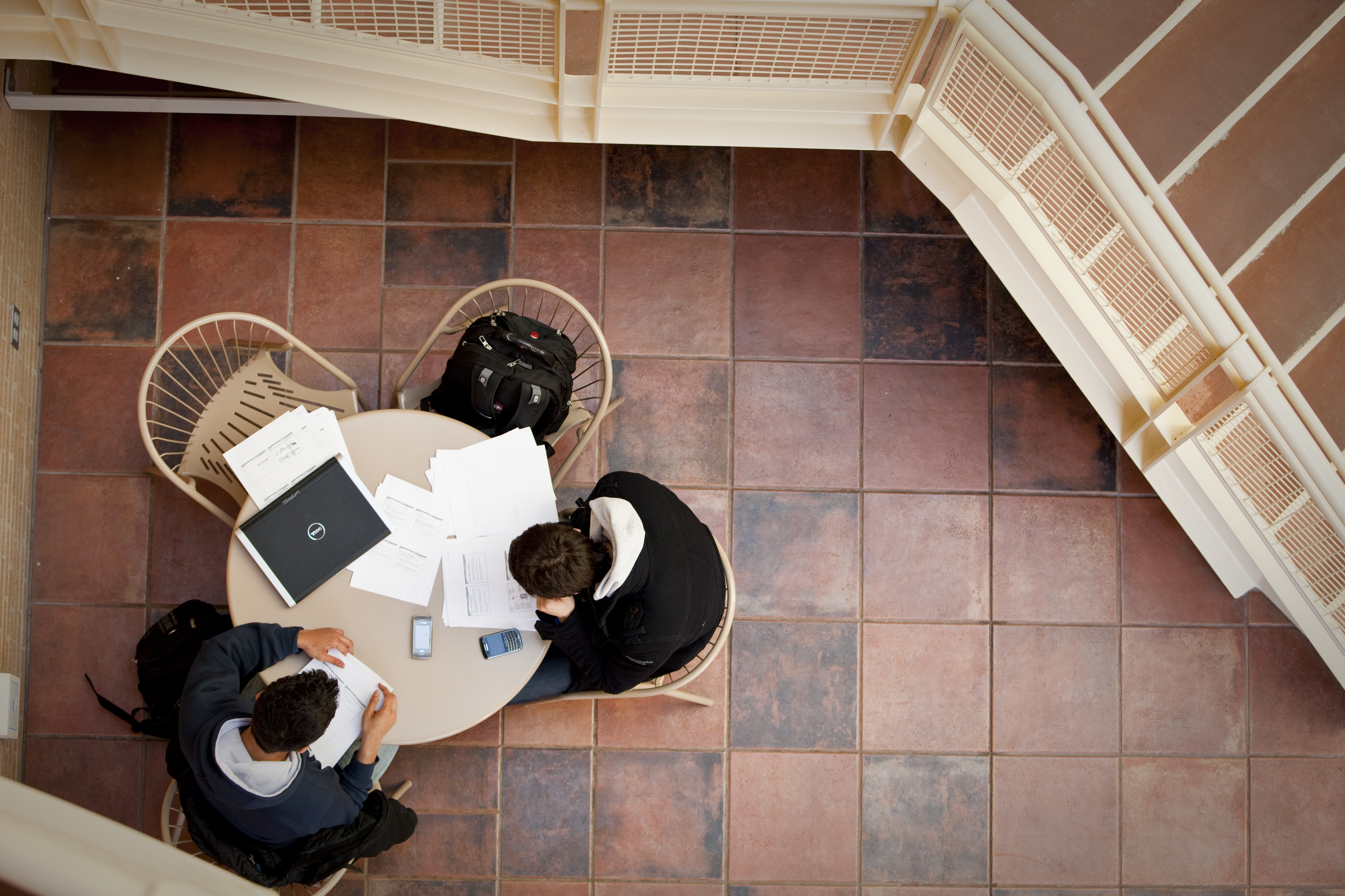 Photo of students working at a table next to a staircase, taken from above