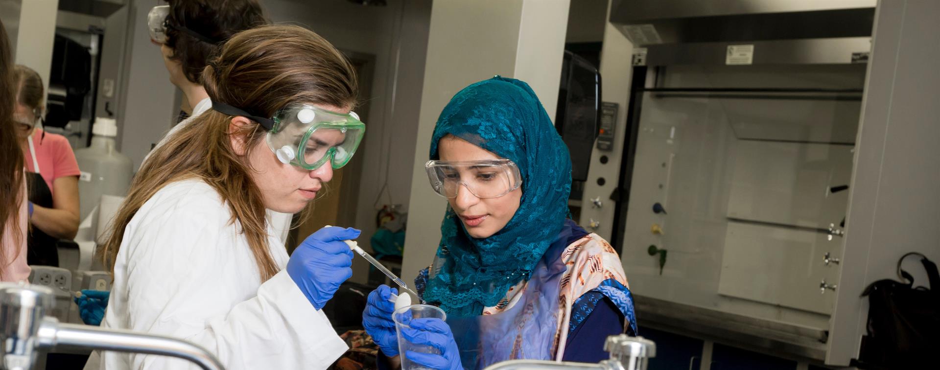 A picture of two women in a lab running an experiment