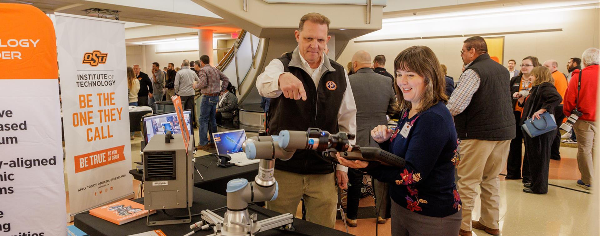 Photo of two people at a booth demonstrating robotic technology