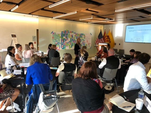 Attendees at ACE's Innovation Lab on student-parents sit at circular tables during a presentation