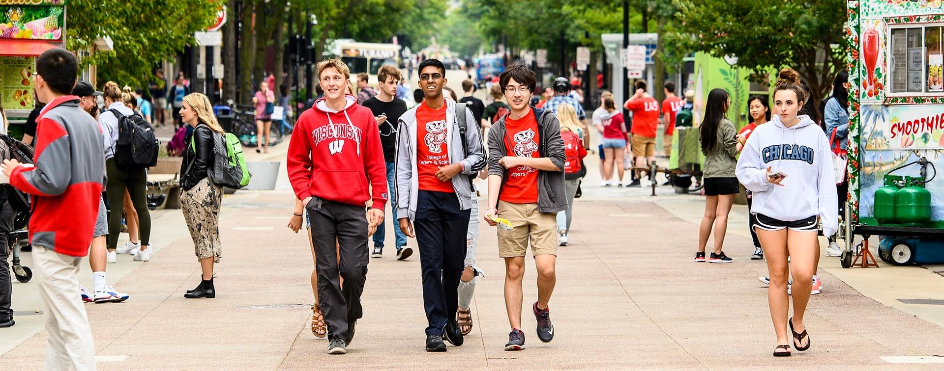 Three students walk in University of Wisconsin merch walk together on campus